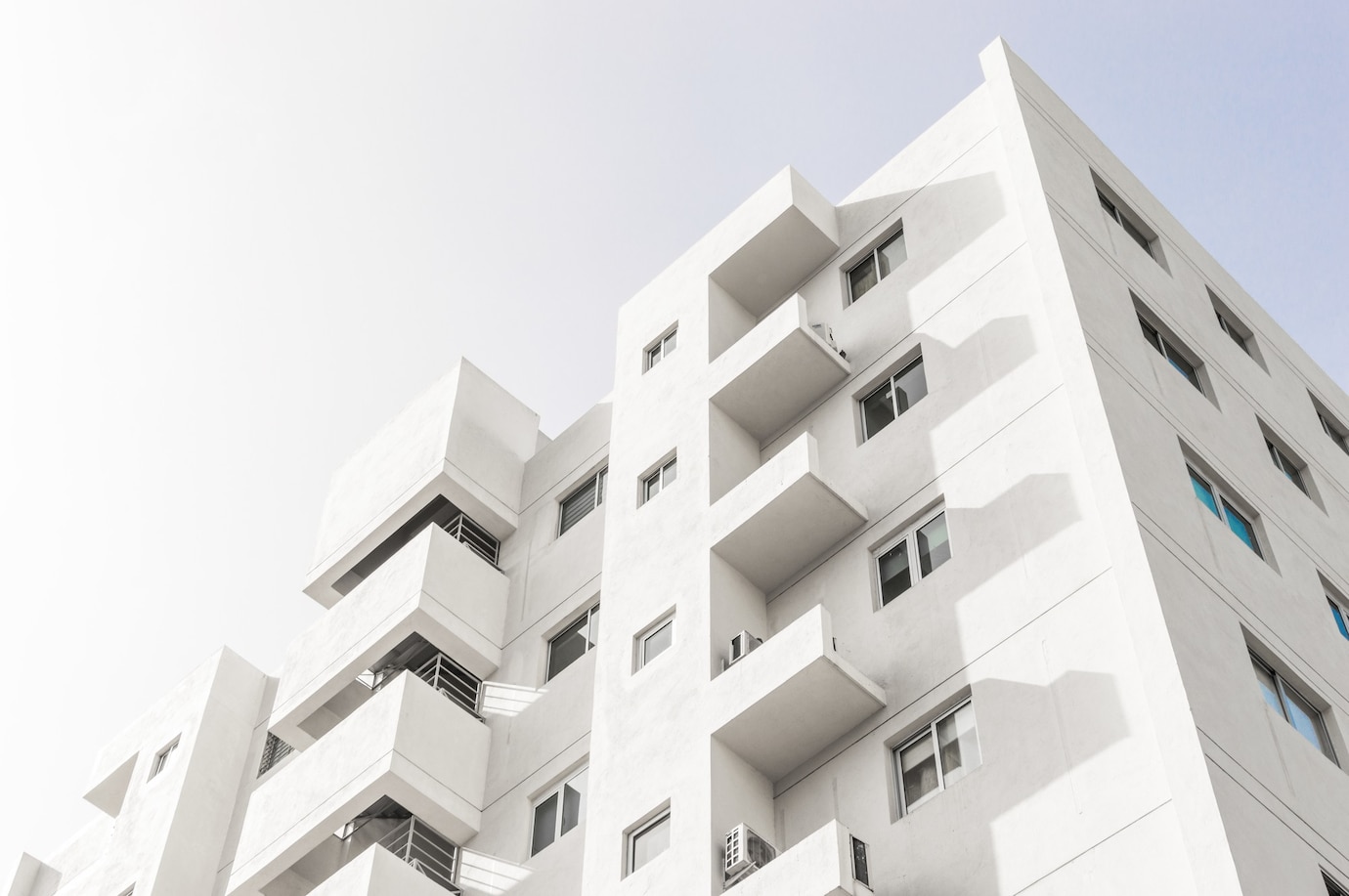 low-angle-shot-facade-white-modern-building-blue-clear-sky_181624-48219